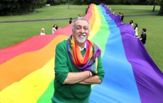 Gilbert Baker with giant trailing rainbow flag